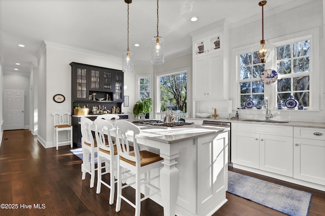 kitchen with a kitchen island, pendant lighting, white cabinets, and sink