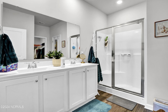 bathroom with hardwood / wood-style flooring, walk in shower, and vanity