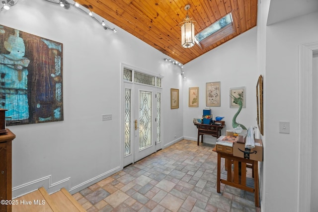 foyer featuring wood ceiling, a skylight, and high vaulted ceiling