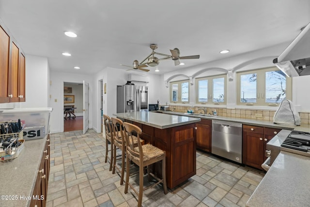 kitchen featuring sink, a breakfast bar, appliances with stainless steel finishes, a center island, and decorative backsplash