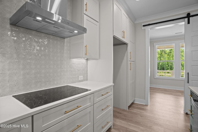 629 Vale Dr, Wilmington, NC 28411 - kitchen featuring wall chimney range hood, black electric cooktop, light countertops, light wood-style flooring, and a barn door