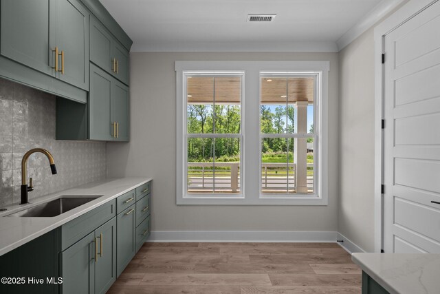 629 Vale Dr, Wilmington, NC 28411 - kitchen featuring a sink, tasteful backsplash, crown molding, light stone countertops, and green cabinets
