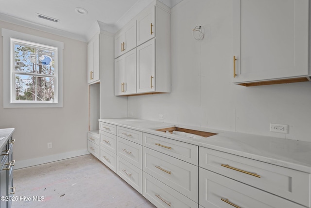 kitchen with white cabinets, visible vents, light countertops, baseboards, and ornamental molding