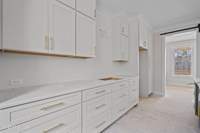 kitchen featuring a barn door, light countertops, white cabinets, and baseboards