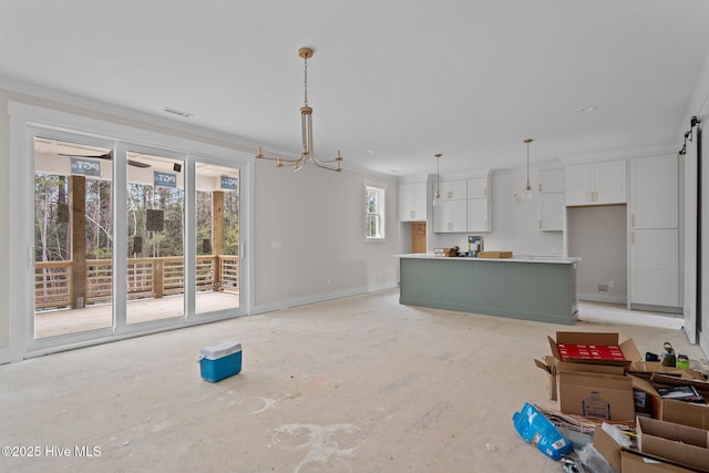 unfurnished living room featuring a barn door, crown molding, and visible vents