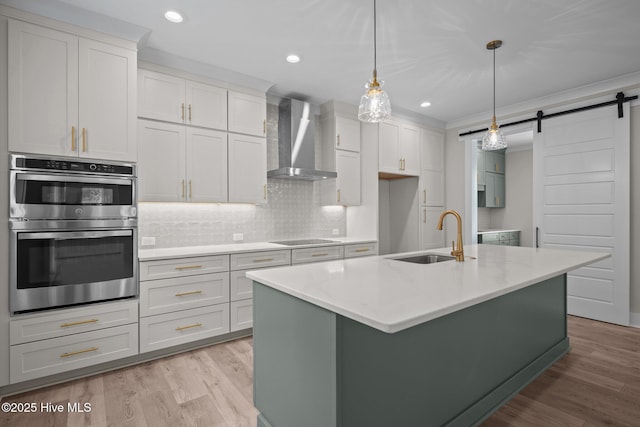 629 Vale Dr, Wilmington, NC 28411 - kitchen featuring a sink, double oven, wall chimney exhaust hood, a barn door, and decorative backsplash