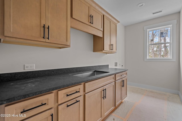 kitchen featuring dark countertops, visible vents, baseboards, and a sink