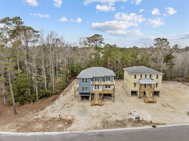 exterior space with a wooden deck, stairway, and a forest view