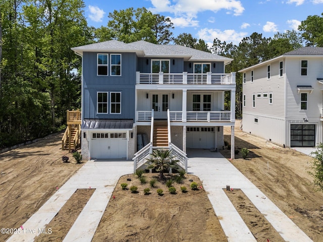 coastal home with board and batten siding, stairs, french doors, and a balcony