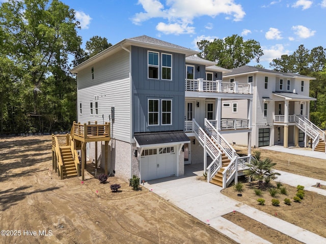 raised beach house with stairway, a shingled roof, a garage, driveway, and board and batten siding