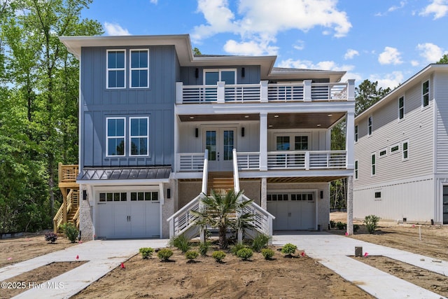 beach home with stairway, a balcony, board and batten siding, an attached garage, and french doors