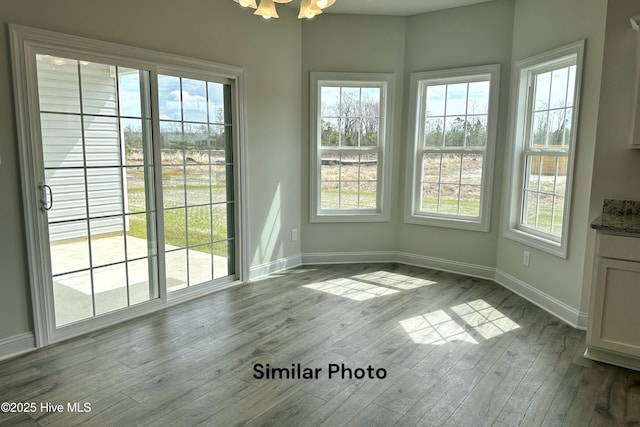 unfurnished dining area featuring light wood-type flooring, plenty of natural light, and a notable chandelier