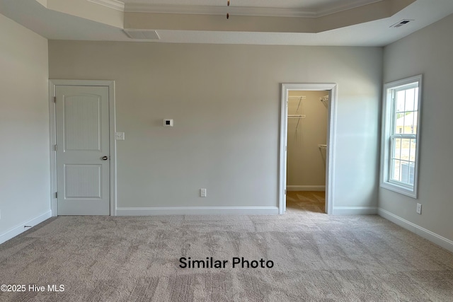 carpeted spare room featuring a raised ceiling and crown molding