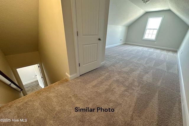 additional living space featuring carpet, a textured ceiling, and lofted ceiling