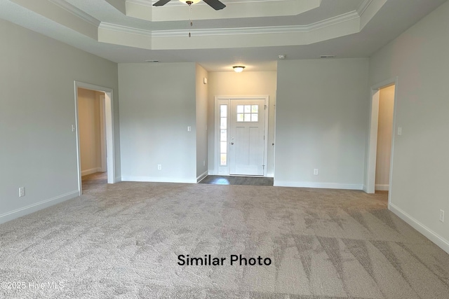 interior space featuring a raised ceiling, ceiling fan, carpet flooring, and crown molding