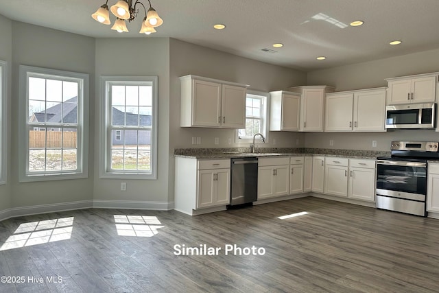 kitchen featuring pendant lighting, stainless steel appliances, and white cabinetry