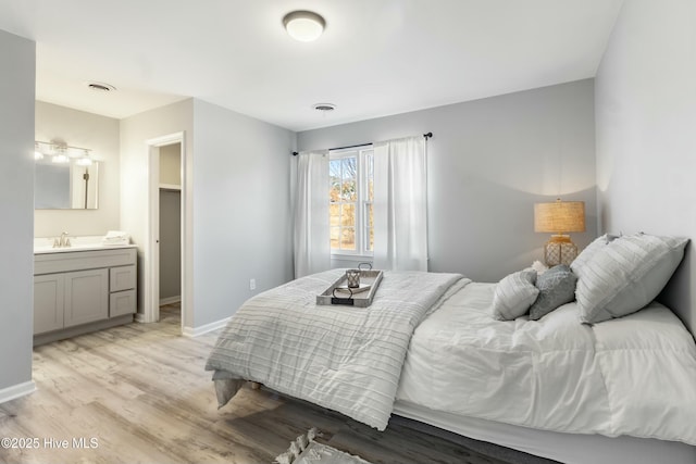 bedroom with sink, light hardwood / wood-style floors, and connected bathroom