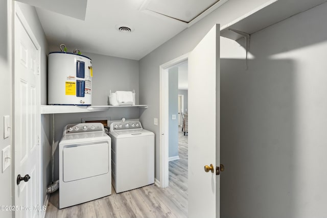 laundry area with washing machine and dryer, electric water heater, and light wood-type flooring