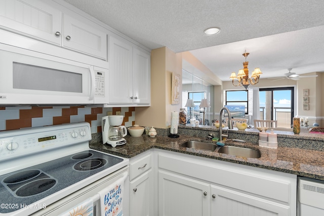 kitchen featuring white appliances, decorative backsplash, white cabinetry, ceiling fan with notable chandelier, and sink