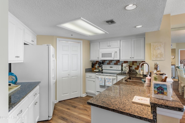 kitchen featuring sink, white cabinetry, white appliances, light hardwood / wood-style flooring, and kitchen peninsula