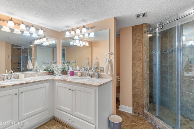 bathroom featuring vanity, a shower with door, tile patterned flooring, and a textured ceiling