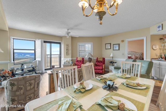 dining space featuring ceiling fan with notable chandelier, a textured ceiling, and hardwood / wood-style flooring