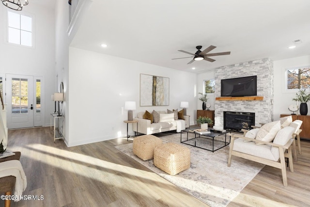 living area with plenty of natural light, visible vents, wood finished floors, and a stone fireplace