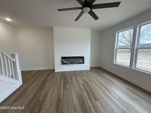 4158 Dixon Rd, Grimesland, NC 27837 - unfurnished living room featuring stairway, dark wood-style floors, baseboards, ceiling fan, and a large fireplace