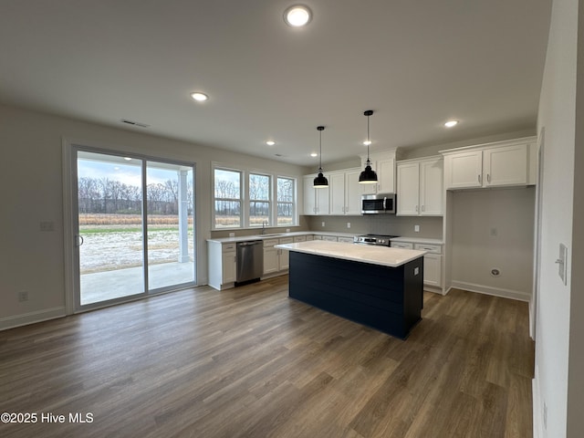 4158 Dixon Rd, Grimesland, NC 27837 - kitchen with wood finished floors, a kitchen island, light countertops, appliances with stainless steel finishes, and white cabinetry
