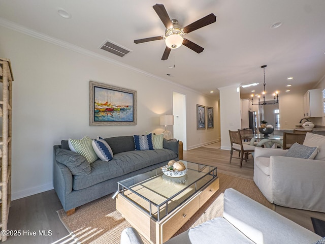 living room with ornamental molding, ceiling fan with notable chandelier, and light hardwood / wood-style flooring