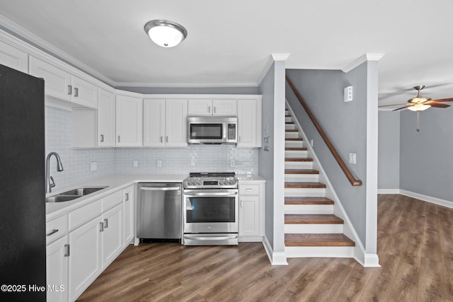 kitchen with stainless steel appliances, a sink, light countertops, and white cabinetry