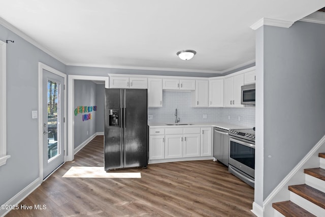 kitchen featuring dark wood-type flooring, a sink, white cabinets, ornamental molding, and appliances with stainless steel finishes