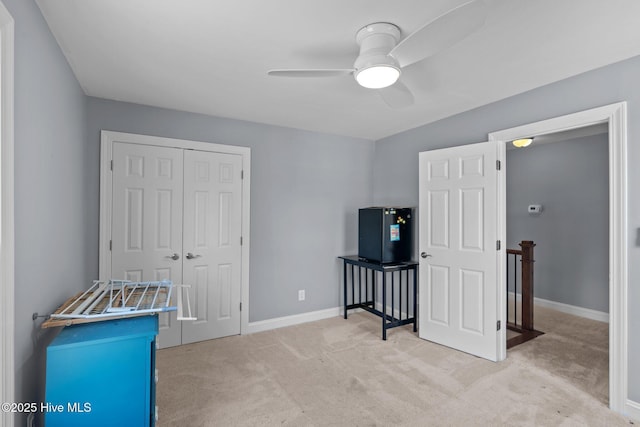 interior space with an upstairs landing, baseboards, a ceiling fan, and light colored carpet