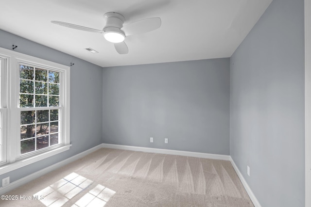 spare room featuring a ceiling fan, light colored carpet, visible vents, and baseboards