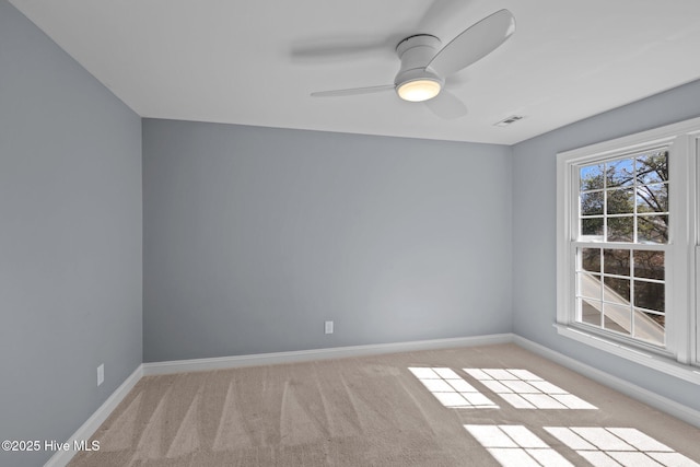 empty room with baseboards, visible vents, a ceiling fan, and light colored carpet