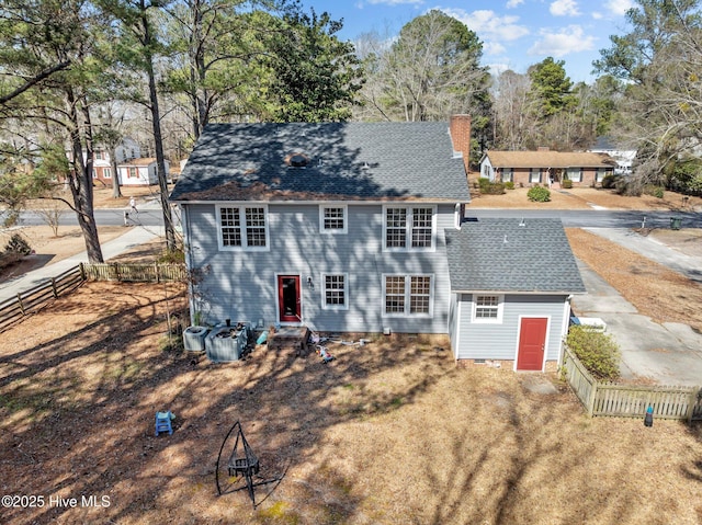 view of front of property with central AC unit, a chimney, a shingled roof, and fence