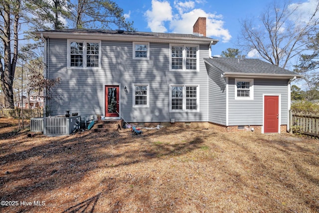 view of front of house with central AC unit, a chimney, a front yard, and fence