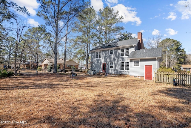 rear view of house with crawl space, roof with shingles, fence, and a chimney