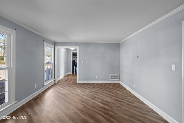 unfurnished room featuring dark wood-style floors, baseboards, visible vents, and crown molding