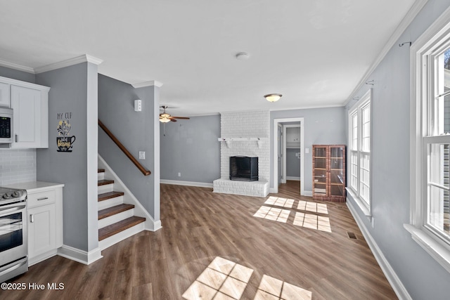 living room featuring baseboards, dark wood-style floors, stairway, crown molding, and a fireplace