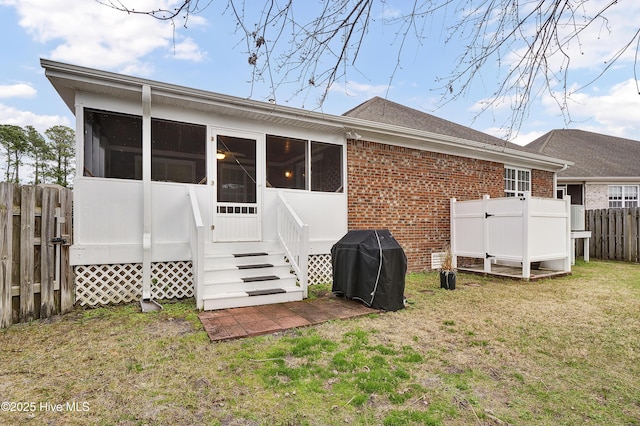 rear view of house featuring a sunroom and a lawn