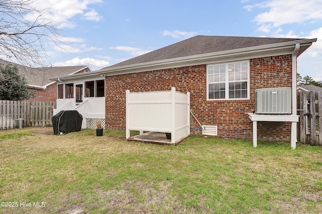 rear view of house featuring central AC and a yard