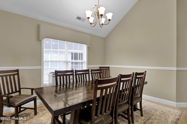 dining area with lofted ceiling and an inviting chandelier