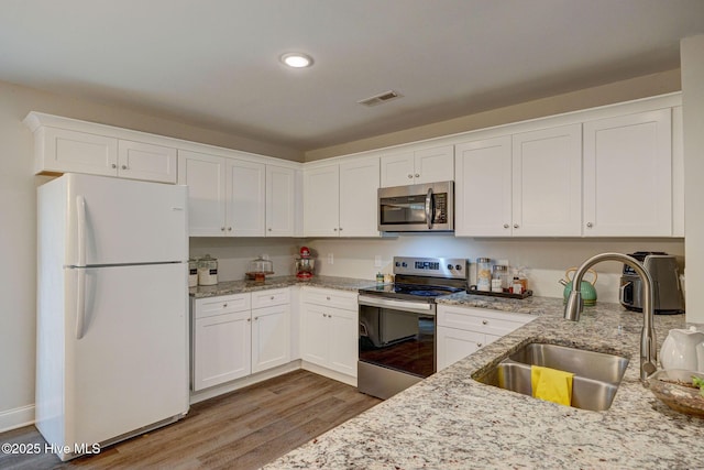 kitchen featuring sink, white cabinets, light stone counters, dark hardwood / wood-style floors, and appliances with stainless steel finishes