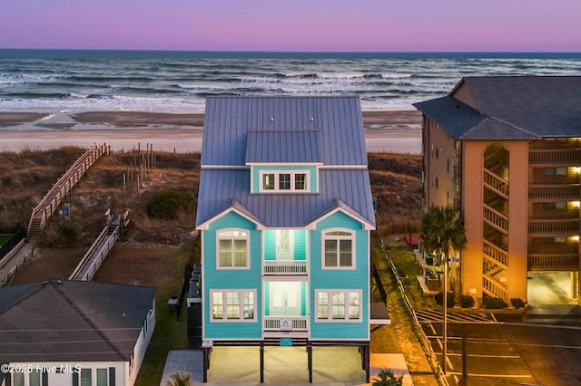 aerial view at dusk with a water view and a beach view