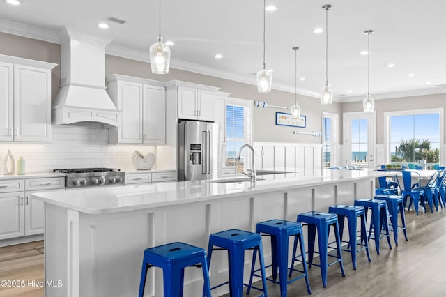 kitchen with white cabinets, a large island, high quality fridge, and custom range hood