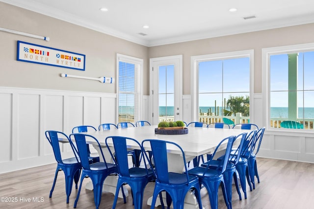 dining area featuring a water view, crown molding, and light hardwood / wood-style floors