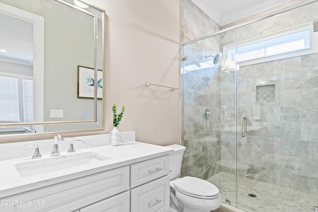 bathroom featuring toilet, vanity, a shower with shower door, and ornamental molding