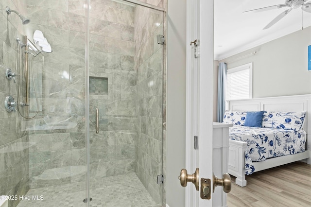 bathroom with a shower with shower door, hardwood / wood-style flooring, ornamental molding, and ceiling fan