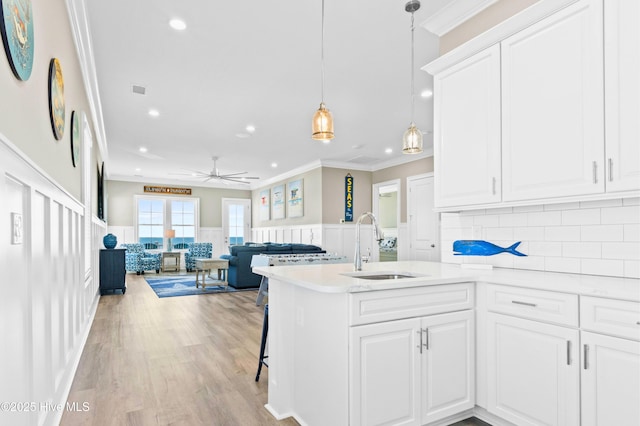 kitchen featuring white cabinets, light hardwood / wood-style floors, sink, kitchen peninsula, and ceiling fan